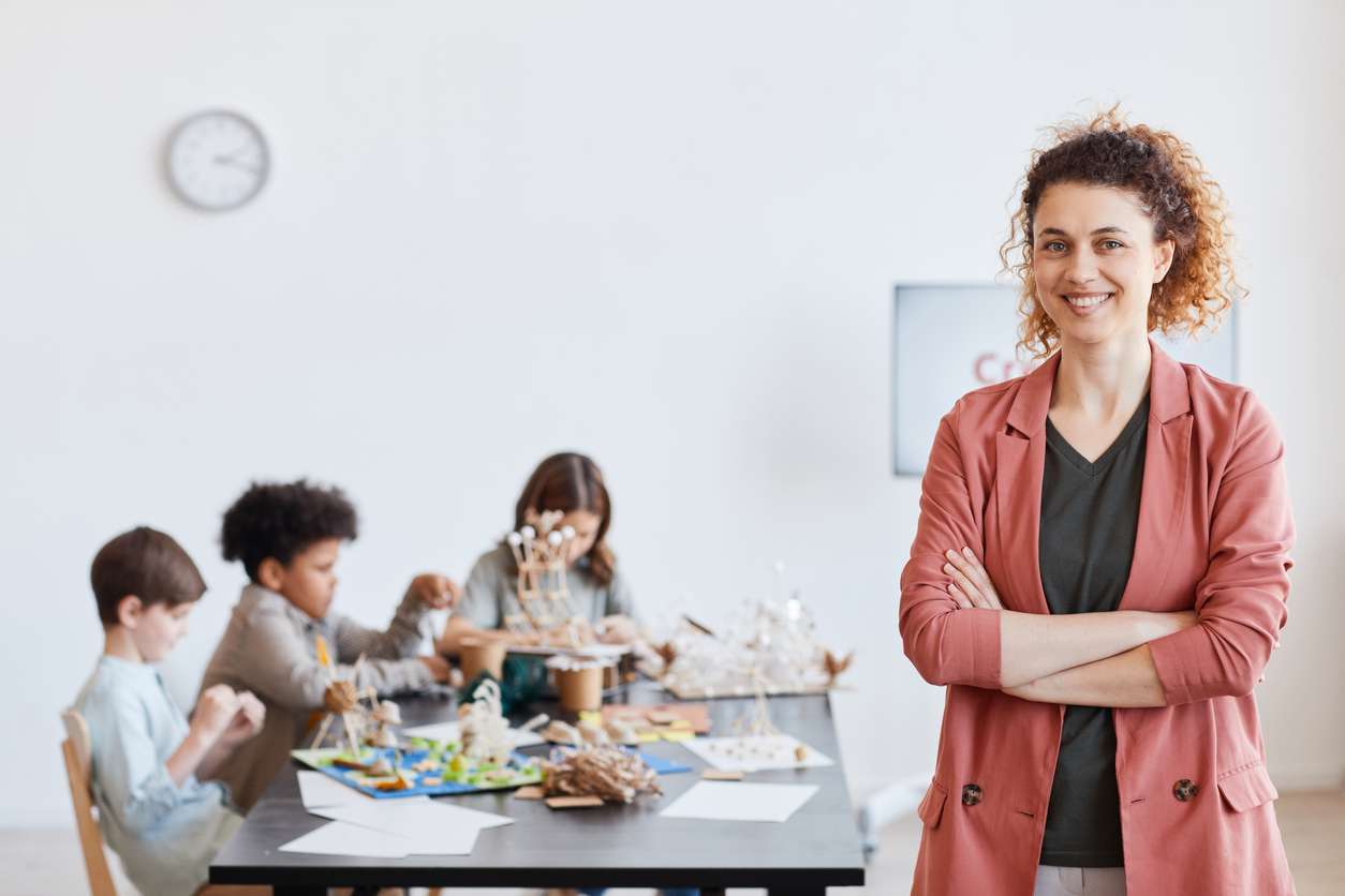 Teacher smiling, students working in the background